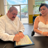 Un hombre y una mujer sentados en una mesa firmando un acta notarial de matrimonio en New Jersey